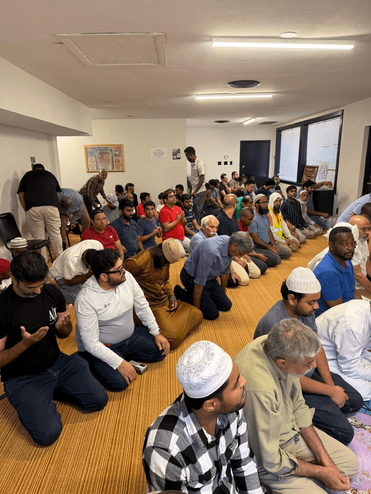 The congregation seated for the khutbah, filling the room wall to wall